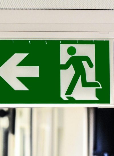 pexels-photo-134065-134065 Green emergency exit sign with directional arrow in a hallway.