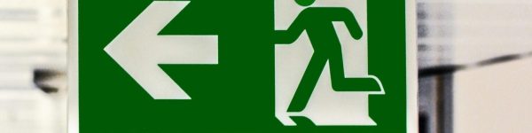 Green emergency exit sign with directional arrow in a hallway.