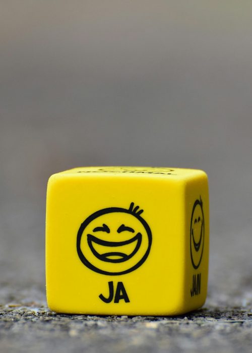 pexels-photo-208147-208147 Close-up of a yellow dice featuring a smiley face emoticon symbolizing happiness and fun.