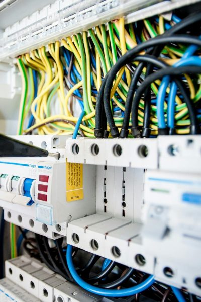 pexels-photo-257736-257736 Hand of electrician working on a circuit breaker panel with colorful wires, ensuring safe electrical connections.
