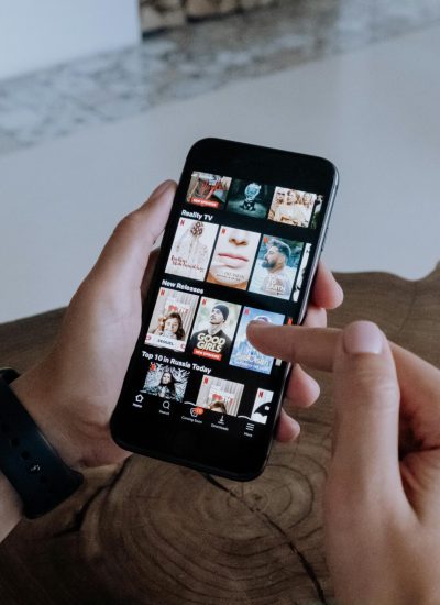 pexels-photo-5081423-5081423 A person using a smartphone to explore and select shows on a streaming platform indoors.
